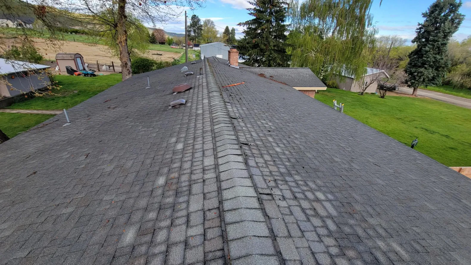 Old worn shingle roof with damaged ridge before reroof