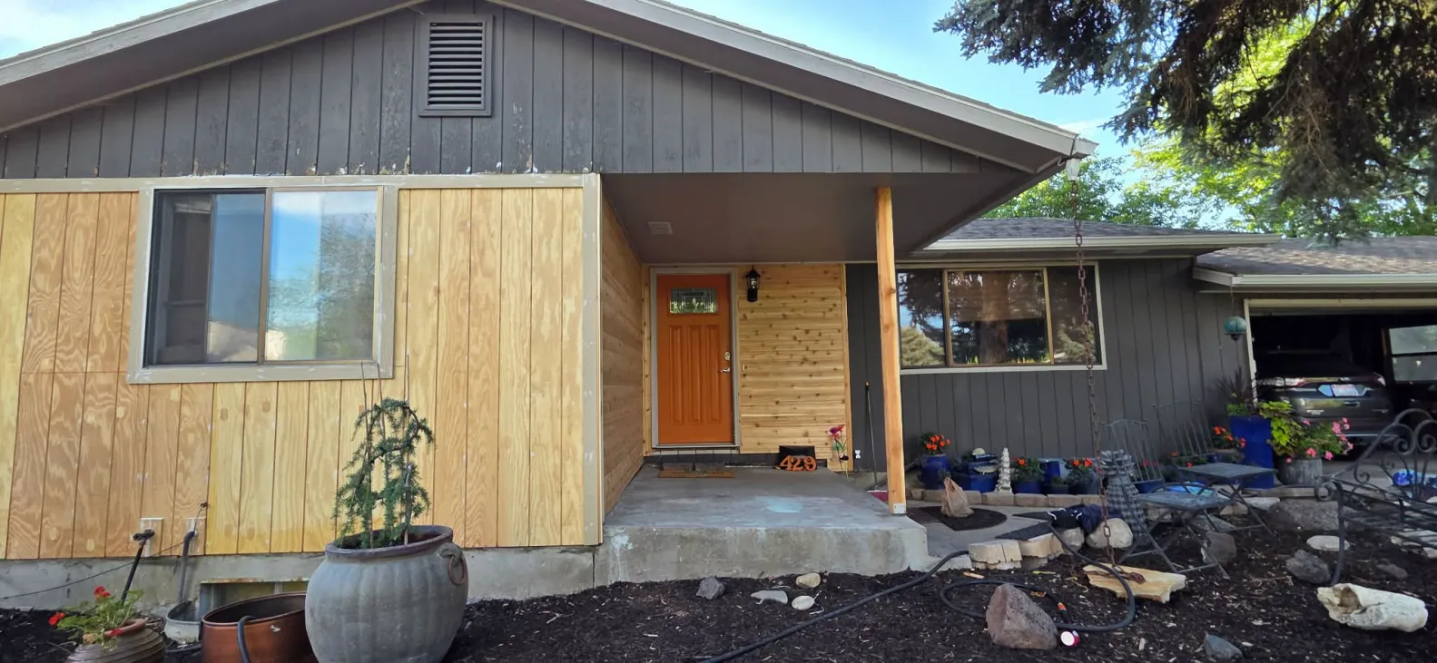 Siding replacement in progress around front entry with cedar accents